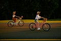 Hipster female friends cycling together along local road