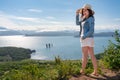Hipster female standing on high mountain against backdrop of panoramic ocean on sunny summer day