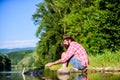 Hipster fishing with spoon-bait. mature bearded man with fish on rod. successful fisherman in lake water. fly fish hobby Royalty Free Stock Photo