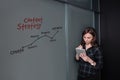 Hipster freelancer woman holding a tablet and standing near a business idea sketch on blackboard