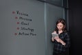 Hipster freelancer woman holding a tablet and standing near a business idea sketch on blackboard