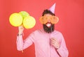 Hipster in giant sunglasses celebrating. Guy in party hat with air balloons celebrates. Man with beard on cheerful face Royalty Free Stock Photo