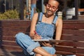 Hipster girl with Afro hairstyle, learns foreign language on distance, writes down records in notepad, learns new