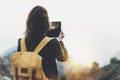 Hipster girl with backpack enjoying sunset on peak of foggy mountain, tourist traveler taking pictures of amazing landscape Royalty Free Stock Photo