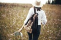 Hipster girl with backpack and map traveling in sunny mountains, walking in  wildflower meadow. Stylish happy woman in hat Royalty Free Stock Photo