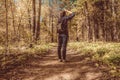 Hipster girl with a backpack is walking on the pathway in forest. Back view photo of female backpacker in the woods Royalty Free Stock Photo