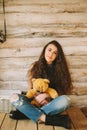 Hipster girl with a bear toy on a wooden background
