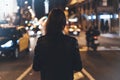 Hipster girl in black leather jacket from back on background illumination glow bokeh light in night atmospheric christmas city