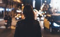 Hipster girl in black leather jacket from back on background illumination glow bokeh light in night atmospheric christmas city, hi