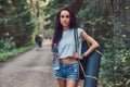 Hipster girl dressed in a shirt and shorts with tourist mat and backpack holds a bottle of water and looking at camera Royalty Free Stock Photo