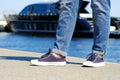 A hipster girl in fashionable ripped jeans and sneakers stands on the pier. Royalty Free Stock Photo