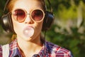 Hipster girl listening to music on headphones and chews the cud. Royalty Free Stock Photo