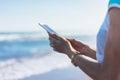 Hipster girl photograph on smart phone gadget in sand coastline, mock up of blank screen. Traveler hold and using in female hand