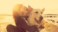 Hipster girl playing with dog at a beach during sunset Royalty Free Stock Photo