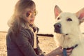 Hipster girl playing with dog at a beach during sunset, strong lens flare Royalty Free Stock Photo