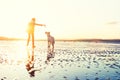 Hipster girl playing with dog at a beach during sunset, strong lens flare Royalty Free Stock Photo