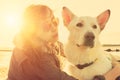 Hipster girl playing with dog at a beach during sunset, strong lens flare effect Royalty Free Stock Photo