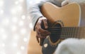 Hipster girl playing guitar in a homelike atmosphere, person studying on musical instrument on glow bokeh Christmas illimination Royalty Free Stock Photo