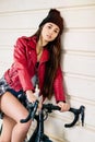 Hipster girl with red jacket posing on her bike Royalty Free Stock Photo