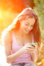 Hipster girl with a smartphone on the background of sunset. Woman with telephone sets Like social networks. Royalty Free Stock Photo