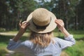 Hipster girl in straw hat standing in the forest. Wanderlust concept. Travelling ideas. Beautiful woman in the nature. Summer