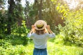 Hipster girl in straw hat standing in the forest. Wanderlust concept. Travelling ideas. Beautiful woman in the nature. Summer