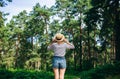 Hipster girl in straw hat standing in the forest. Wanderlust concept. Travelling ideas. Beautiful woman in the nature. Summer