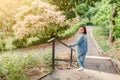 Girl walks along the path in the city park and looking at the blooming trees at spring time Royalty Free Stock Photo