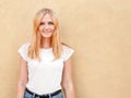 Hipster girl wearing blank white t-shirt and jeans posing against rough street wall, minimalist urban clothing style Royalty Free Stock Photo