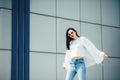 Hipster girl wearing blank white t-shirt, jeans and sunglasses posing against rough street wall, minimalist urban clothing style. Royalty Free Stock Photo