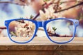 hipster glasses on a wooden table in front of cherry tree