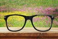 hipster glasses on a wooden table in front of the field flowers