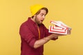 Hipster guy in beanie hat and checkered shirt peeking inside gift box, screaming in amazement and happiness