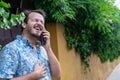 Hipster guy bearded laughing in the street while speak in a phone call. Young adult talking in cellular with a friend, listening a