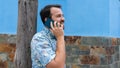 Hipster guy leaning in pole speaking by cellphone having a dialogue with his friend, consulting. Trendy person using telephone in Royalty Free Stock Photo