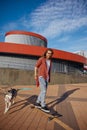 Hipster guy riding skateboard with dog on leash enjoying summer time Royalty Free Stock Photo