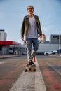 Hipster guy riding skateboard prefers eco-friendly transportation among city Royalty Free Stock Photo