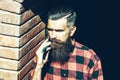 Hipster with haircut and thick beard holding old fashion razor with serious face. Bearded client visiting barber shop