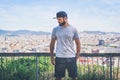 Hipster handsome male model with beard wearing gray blank t-shirt and a black snapback cap with space for your logo or