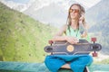 Hipster handsome man with skateboard and mobilephone listening to music Royalty Free Stock Photo