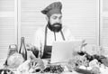 Hipster in hat and apron learning how to cook online. Culinary education online. Elearning concept. Man chef searching Royalty Free Stock Photo