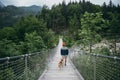 Hipster hiker man and dog on suspension bridge