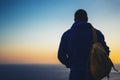Hipster hiker tourist with backpack looking of amazing seascape sunset on background blue sea, guy enjoying ocean horizon Royalty Free Stock Photo