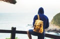 Hipster hiker tourist with backpack looking on seascape sunset, background blue sea Royalty Free Stock Photo