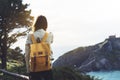 Hipster hiker tourist with backpack looking on seascape sunset, background blue sea and mountain, girl enjoying ocean horizon Royalty Free Stock Photo