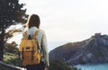 Hipster hiker tourist with backpack looking on seascape sunset, background blue sea and mountain, girl enjoying ocean horizon Royalty Free Stock Photo