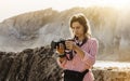 Hipster hiker tourist with backpack taking photo of amazing seascape sunset on camera on background mountains, photographer enjoy Royalty Free Stock Photo