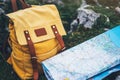 Hipster hiker tourist yellow backpack closeup and navigation map europe on background green grass nature, blurred panoramic landsc