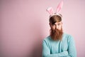 Hipster Irish man with beard wearing easter rabbit ears over isolated pink background skeptic and nervous, disapproving expression Royalty Free Stock Photo