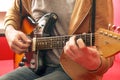 Casually dressed young man with guitar playing songs in the room at home. Online guitar lessons concept. Male guitarist practicing